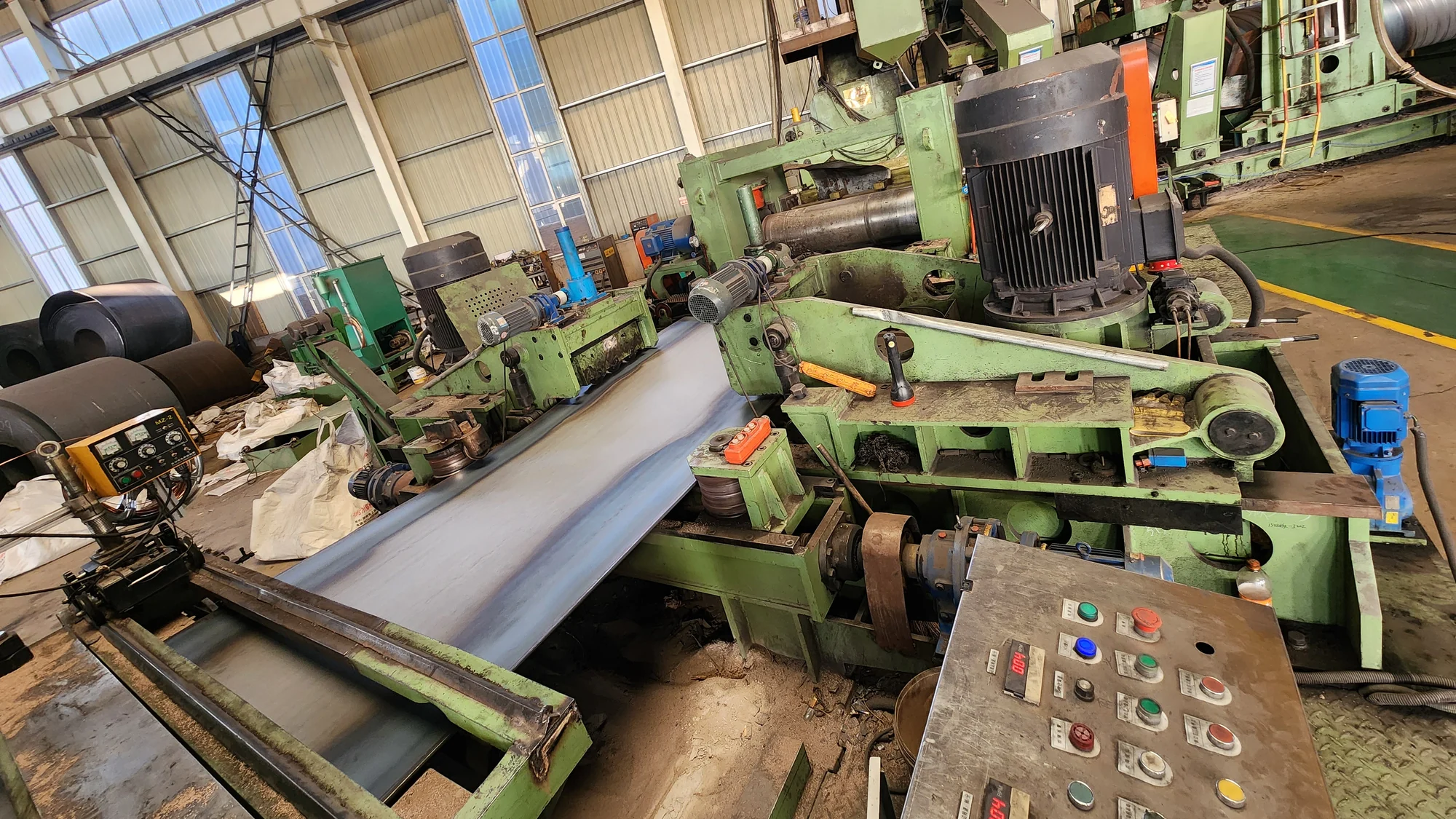Steel strip being fed towards the forming section of a spiral mill