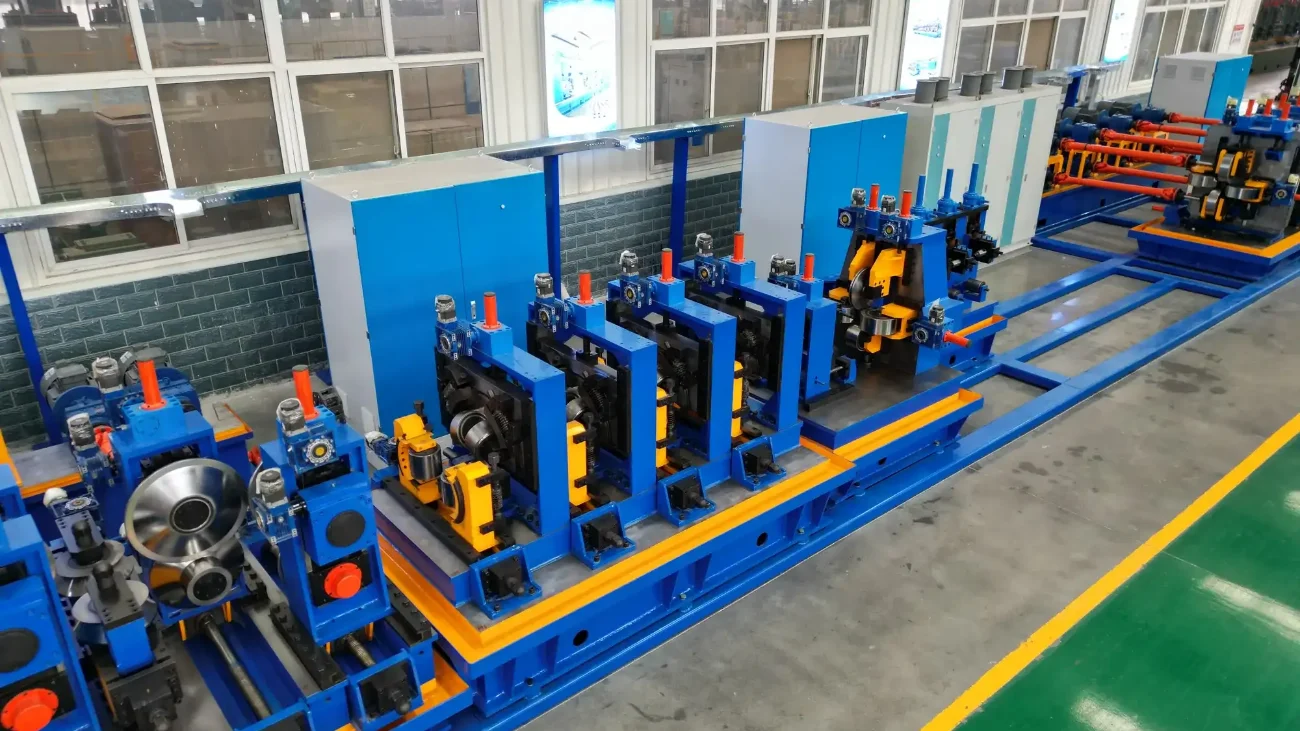 Blue roll forming stands of a tube mill in a white-walled workshop