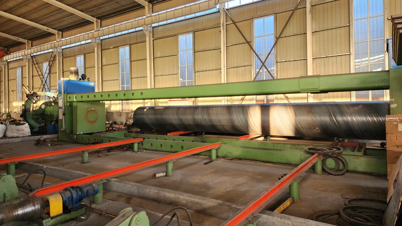 Spiral welded pipe leaving the mill on the run-out rack